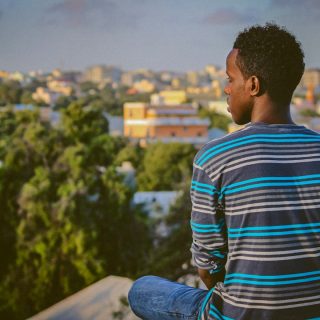 a man sitting on a ledge overlooking a city